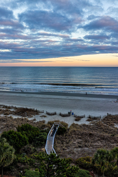 默特尔海滩城市与空中高角度的观点俯瞰大西洋在多云戏剧性的日落与木板海滩通过沙丘和海燕麦植物海岸图片下载