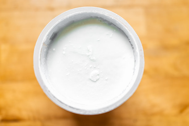 紧闭的平顶躺下俯瞰的有机全脂牛奶包装容器平滑和奶油香草酸奶酸奶在木桌上图片下载