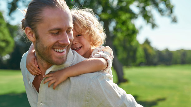 可爱的小男孩在公园里玩耍，他的父亲让儿子骑在他的肩膀上图片下载