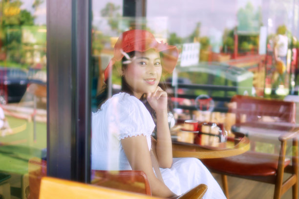 亚洲女人微笑着透过窗户看，亚洲女孩在咖啡馆放松图片下载