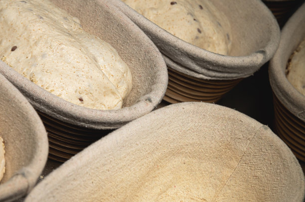 生的面包面团，上面撒着木条，上面盖着布。工艺制作面包图片下载