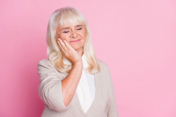 照片肖像的妇女有牙痛触摸脸颊与手孤立在柔和的粉红色背景图片下载