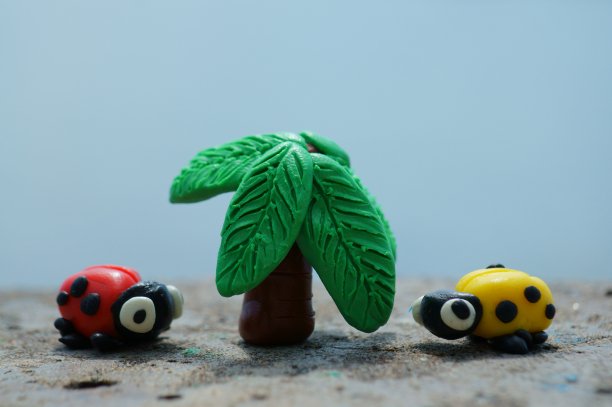 两只瓢虫和一棵橡皮泥做成的棕榈树。图片下载