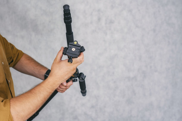 一名男子摄影师手持专业三脚架拍摄照片和视频。图片下载