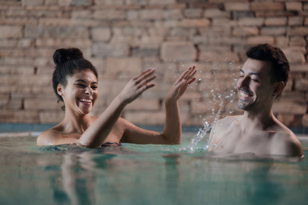 幸福的年轻情侣在游泳池里嬉戏。图片下载