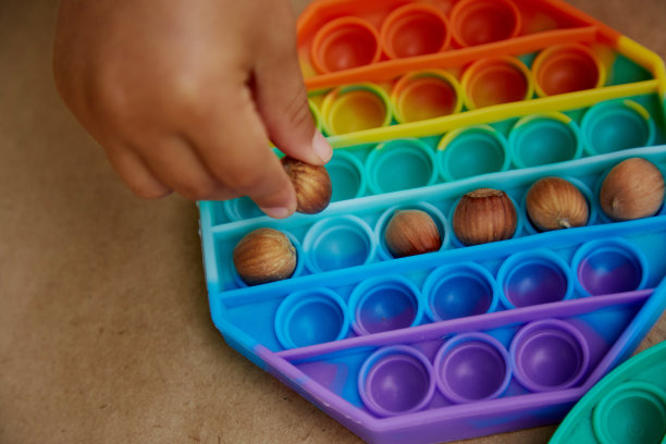 小孩用玩具和榛子玩游戏。游戏为运动技能的发展。彩虹触摸感官的烦躁。前视图。高质量的照片图片下载