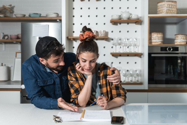 年轻幸福的新婚夫妇站在他们的厨房里，想要列一份名单，邀请家人和朋友来参加他们的婚礼图片下载
