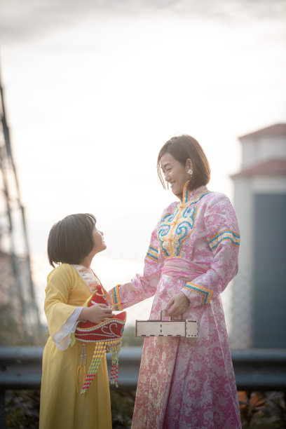 亚洲华人妈妈和女儿穿着传统服装，手拿月饼盒享受月饼节图片下载