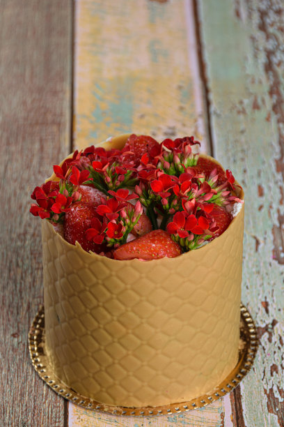 礼服蛋糕，包裹在一层有质感的咸焦糖巧克力，草莓和红色卡拉凤花(垂直照片)。图片下载