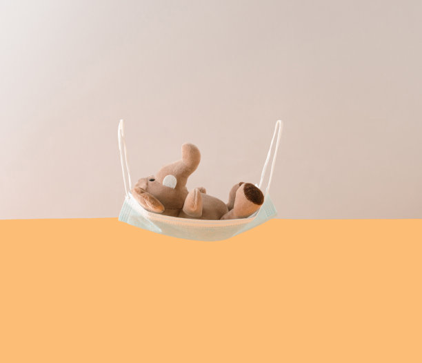 灰色的大象玩具躺在面具上，就像金色和银色背景下的秋千。抽象艺术的概念。图片下载