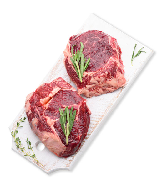 生牛肉肋眼配上迷迭香和百里香放在白色木制砧板上，俯视图。食物被隔离在白色背景上图片下载
