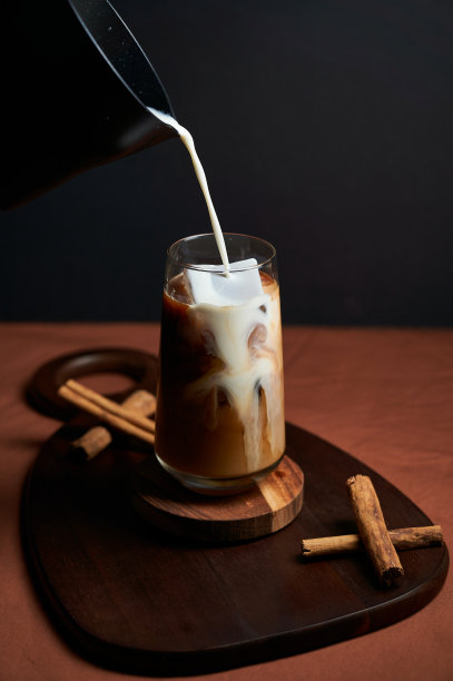 用肉桂棒把牛奶倒在热而新鲜的肉桂咖啡上图片下载