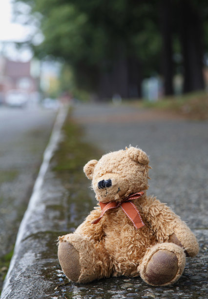 一只被遗弃、衣衫褴褛的泰迪熊孤零零地坐在人行道上图片下载