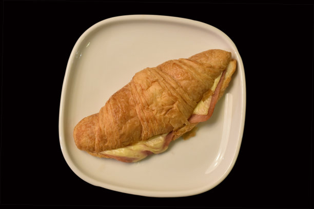 黑色地面上的火腿和奶酪牛角面包图片下载