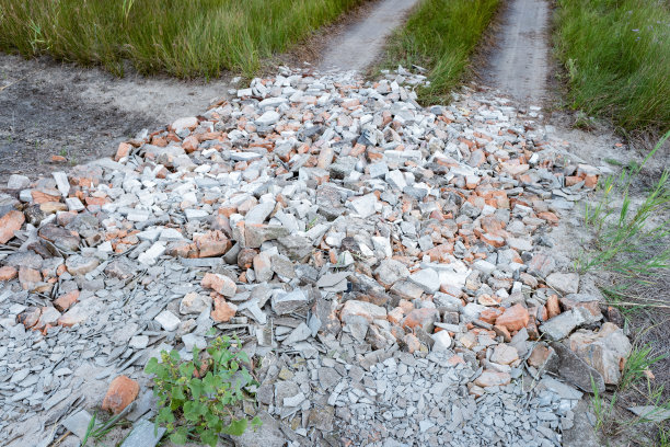 乡村道路上的坑洼被破碎的砖块、石头、灰泥和建筑垃圾所覆盖图片下载