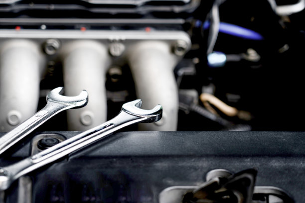 发动机室上的扳手的黑暗照片:技工检查和修理一辆破车在汽车服务车库图片下载