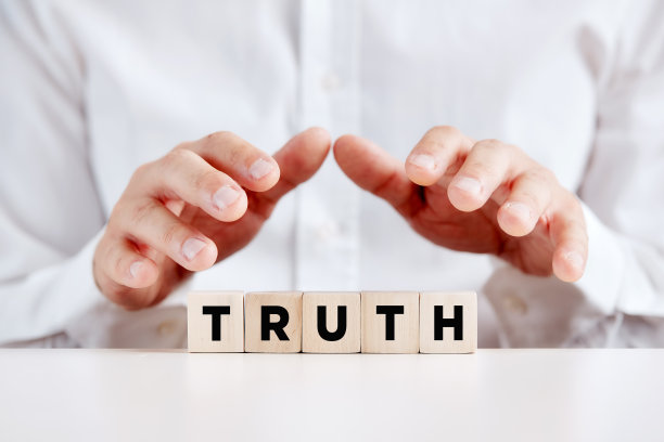 男人用手保护着木制的立方体，上面写着“真理”两个字。图片下载