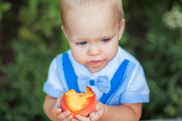 美味的桃子和有趣的小孩。第一次给孩子喂桃子…图片下载