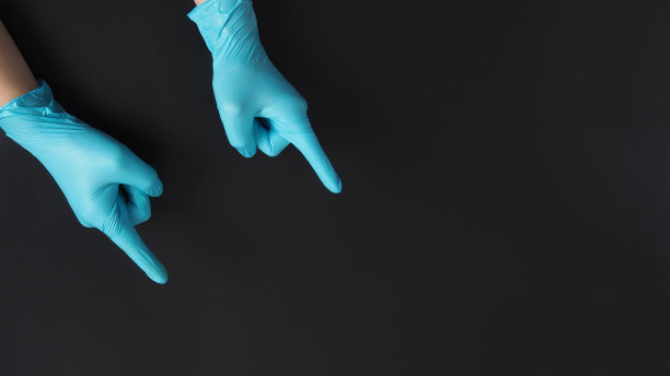 双手戴蓝色医用手套，手指放在黑色背景上。图片下载
