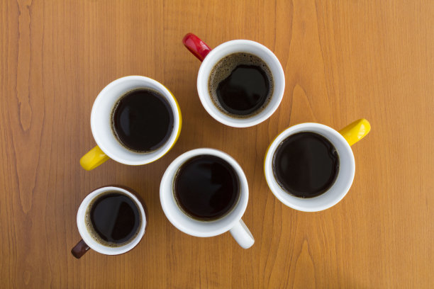 构图与黑色咖啡在明亮的杯子中心棕色木制背景。前视图。图片下载