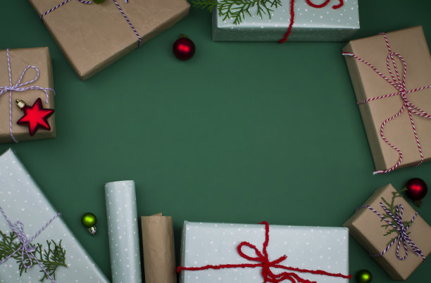 圣诞节布局:盒子里的礼物，杉木树枝，玩具，包装纸上的绿色背景，顶部视图，平面，复制空间图片下载
