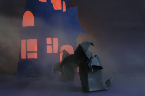 在一所黑暗的房子的背景下，雾中有两个带着红光的黑影。黑色的纸为万圣节节日的鬼魂图片下载