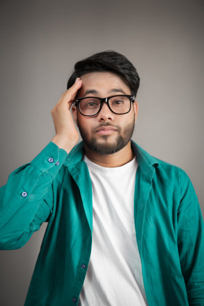 一幅戴眼镜的印度年轻人的肖像，他正遭受严重的头痛。图片下载