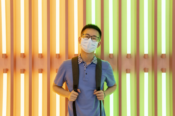 亚洲男子在霓虹灯前的面具后微笑图片下载