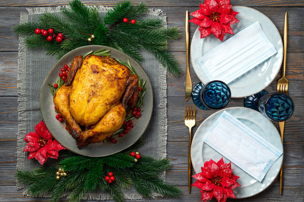 烤鸡或火鸡在节日的餐桌上与节日装饰和木制背景的保护面具的圣诞晚餐，俯视图。在新冠疫情中，圣诞节、新年是概念图片下载