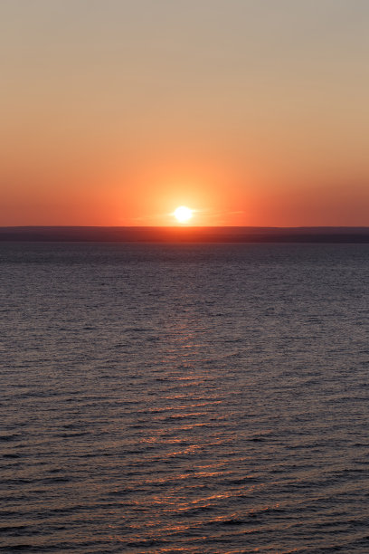 美丽多彩的日落在海上。红日无云。海平线。鸟瞰图。景观。明信片图片的概念。海面上的光波图片下载