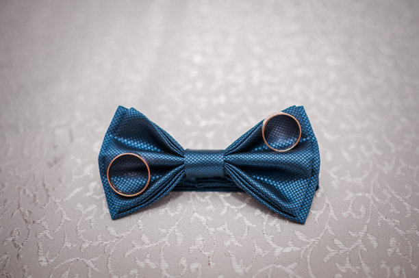 背景是深蓝色的领结和结婚戒指图片下载