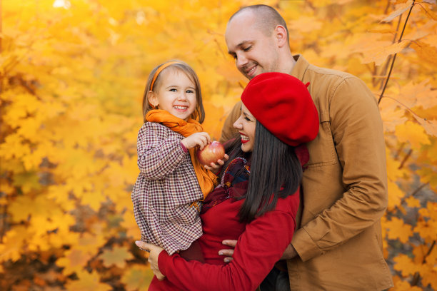 在秋叶的背景下，一个家庭和一个小女儿的肖像。图片下载