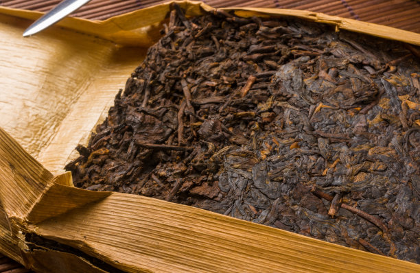 中国压普洱茶在竹叶包装和茶刀在竹席，特写，宏观图片下载