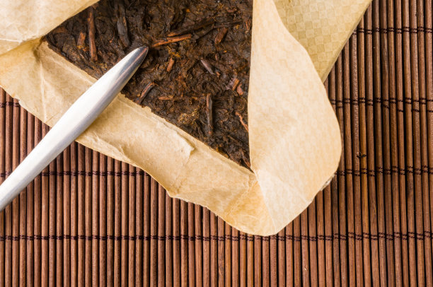 中国人压在包装纸上的普洱茶和竹席上的茶刀，特写，宏观图片下载