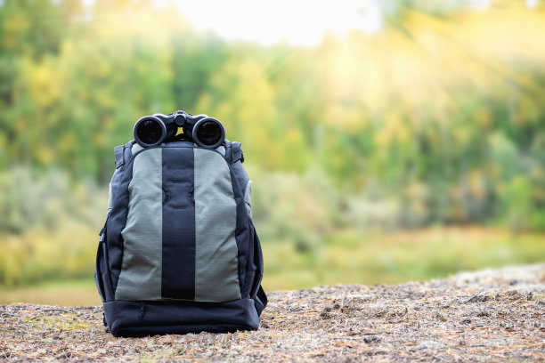 把双筒望远镜和背包放在河的高处。运动器材。图片下载