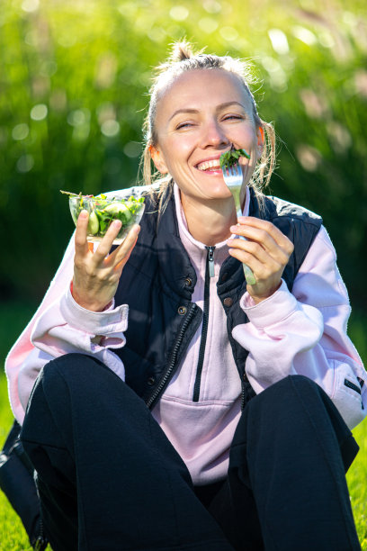 美丽的白人女子吃沙拉在绿色的自然背景图片下载