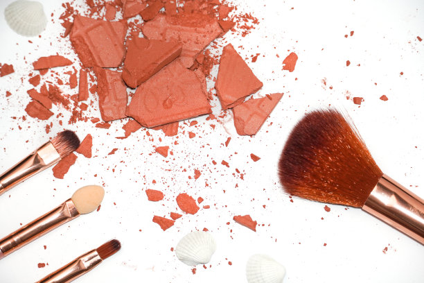 化妆品样本的创造性照片。青铜色的眼影被打破，白色背景上有化妆刷图片下载