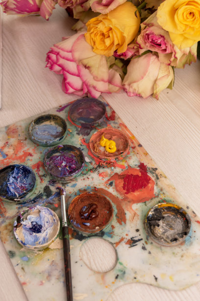 书桌上用调色板布满了五颜六色的颜料，画笔和花束上五颜六色的玫瑰，艺术品和装饰物，物体纹理风格图片下载