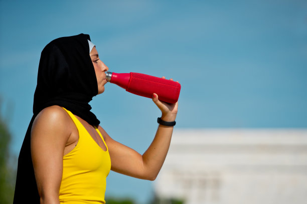 戴着头巾的运动装穆斯林妇女在喝水图片下载