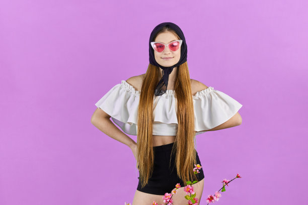 快乐的模特穿着时髦的春装在蓝色背景下摆姿势的时尚肖像。漂亮的金发年轻女孩带着花。春天的概念。图片下载