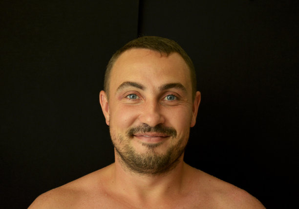 黑色背景上的人。一个男人的嘴唇上挂着微笑，脸上留着黑胡子图片下载