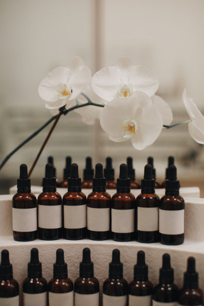 收集套空透明的棕色滴管瓶与移液管和白色花朵的背景。图片下载