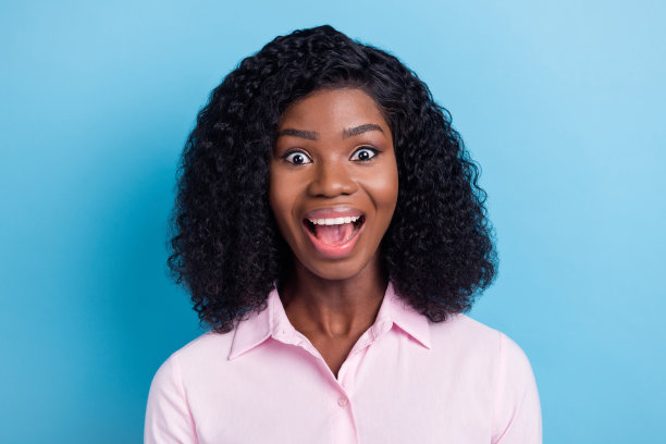 可爱的照片印象深刻的深色皮肤的女士穿着粉红色的衣服张开嘴孤立的蓝色背景图片下载
