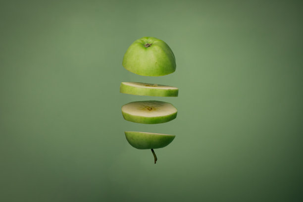 绿色背景上的绿色苹果切片。把切开的苹果悬浮在空中图片下载
