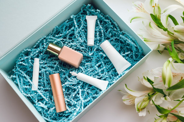 化妆品盒的样品和微型霜，血清，香水，口红和粉底在蓝色包装刨花-平图片下载