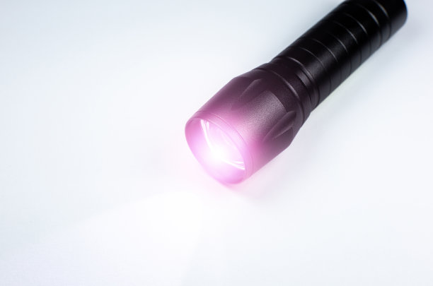 黑色手电筒和白色背景上的一束光。近距离的照片。图片下载