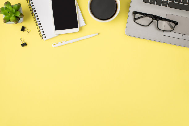 俯视图照片的笔记本电脑杯饮料玻璃杯植物笔夹夹夹和智能手机的螺旋笔记本上孤立的淡黄色背景与空白图片下载