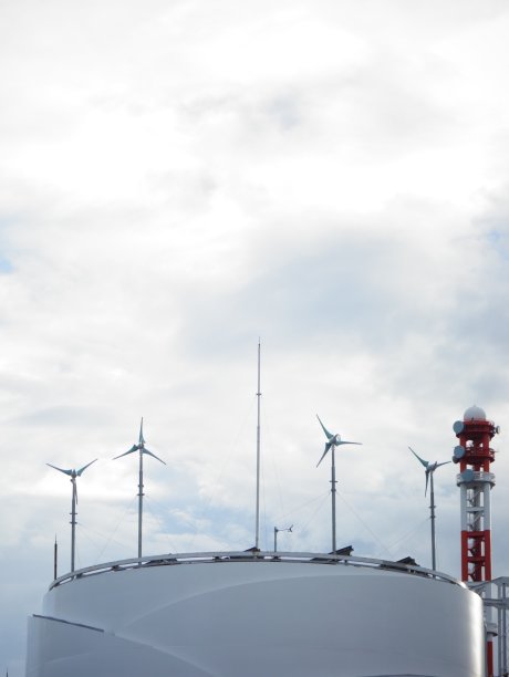 日本东京，白色现代建筑屋顶上的小型风力涡轮机，背景是红白相间的通讯塔图片下载