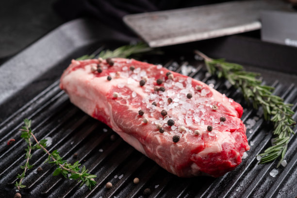 一份完美的生牛排夹头牛肉卷，放在黑色烤盘上，加上调味料图片下载