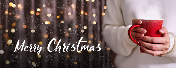 圣诞快乐。穿着白色毛衣的女人手里拿着圣诞热饮或红色杯子里的咖啡。闪烁的背景与雪和光散景。在卡片或横幅上添加文字图片下载